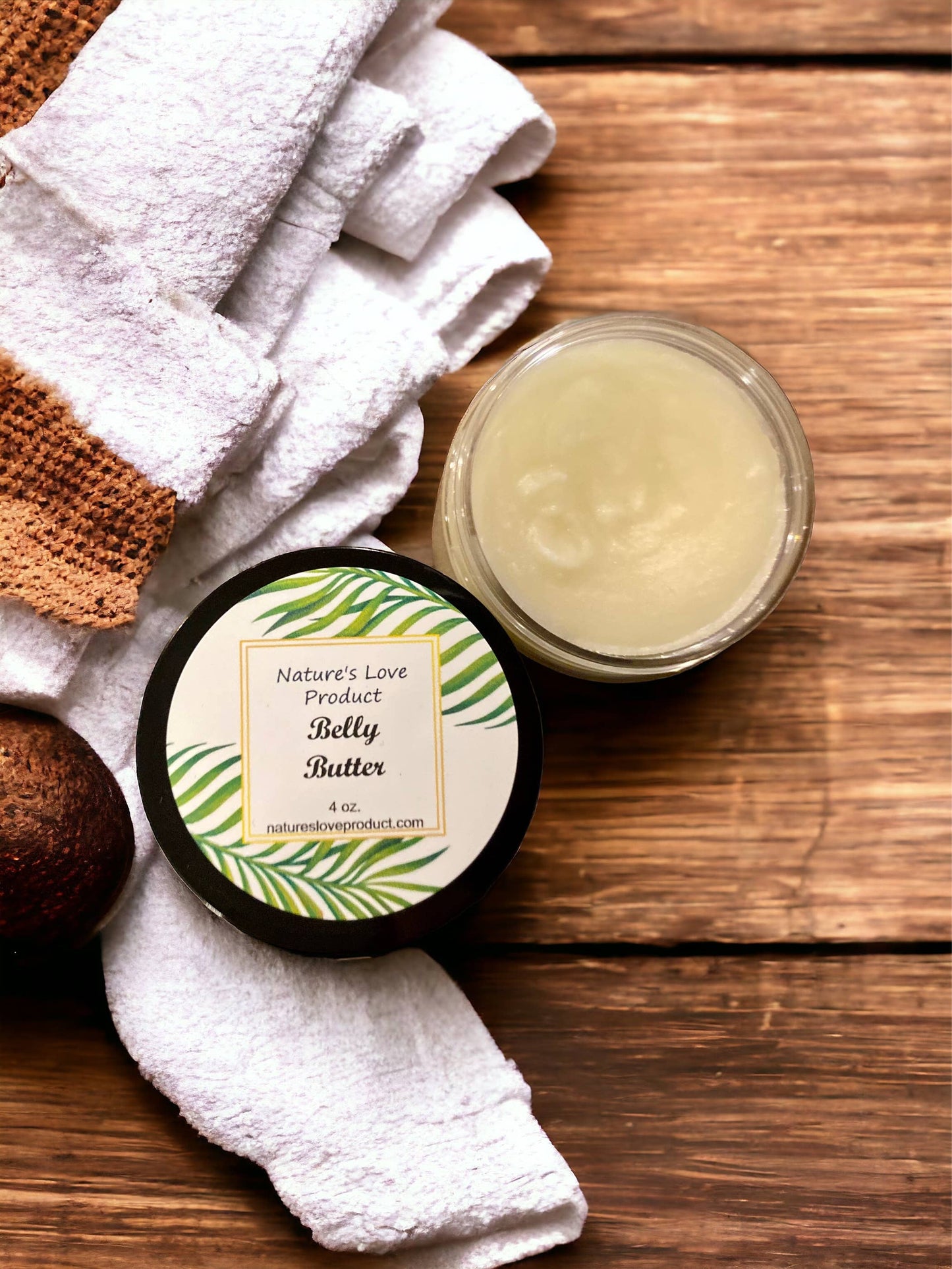 Open jar of Nature's Love Belly Butter on wooden surface with white and brown towel nearby