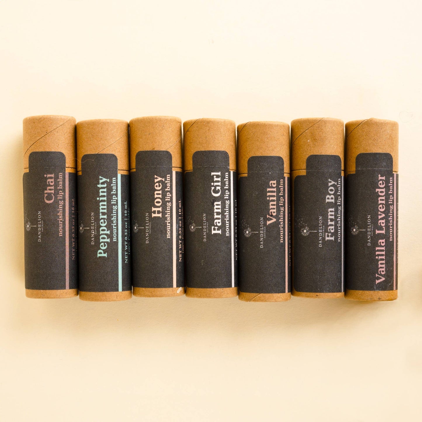 Seven natural nourishing lip balm tubes in kraft paper packaging with flavors Chai, Pepperminty, Honey, Farm Girl, Vanilla, Farm Boy, Vanilla Lavender