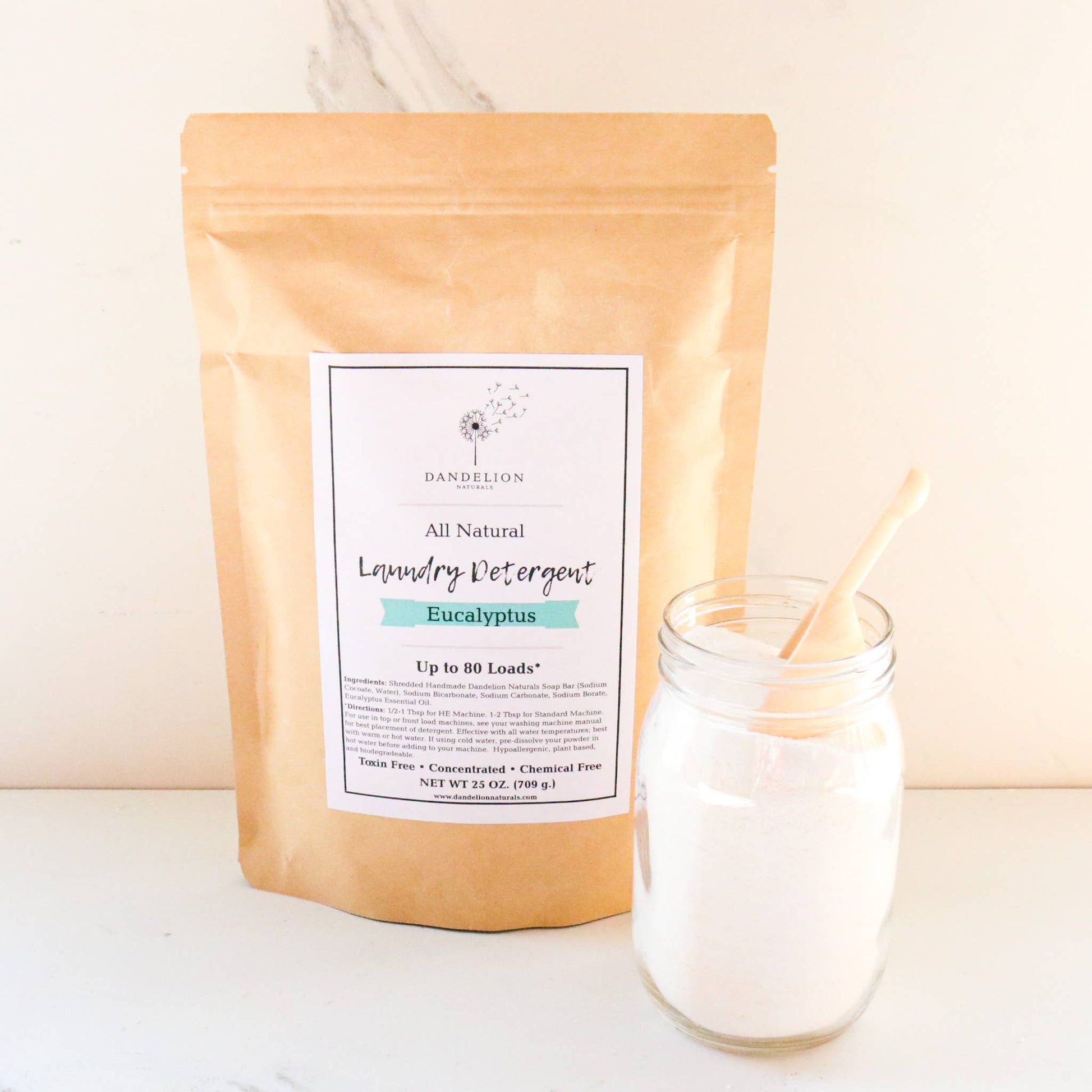 All natural eucalyptus laundry detergent powder in kraft paper pouch with glass jar and wooden scoop