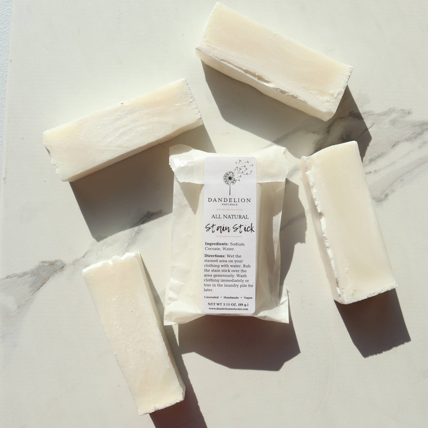 Dandelion Naturals all natural stain stick with five white soap bars on marble surface