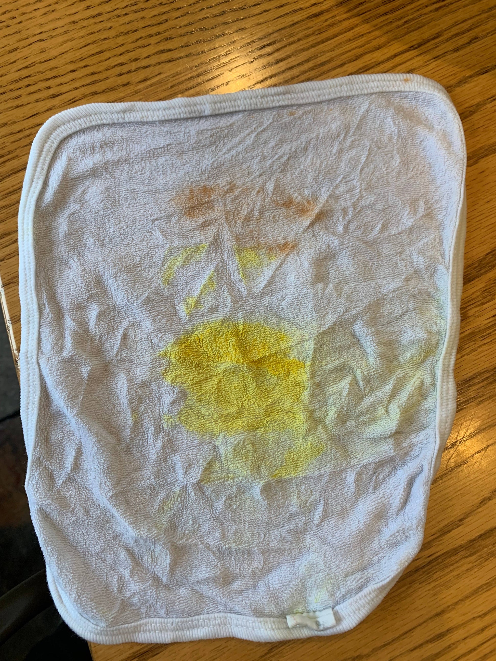 White cloth with yellow and brown stains on wooden surface, natural cleaning remedy concept