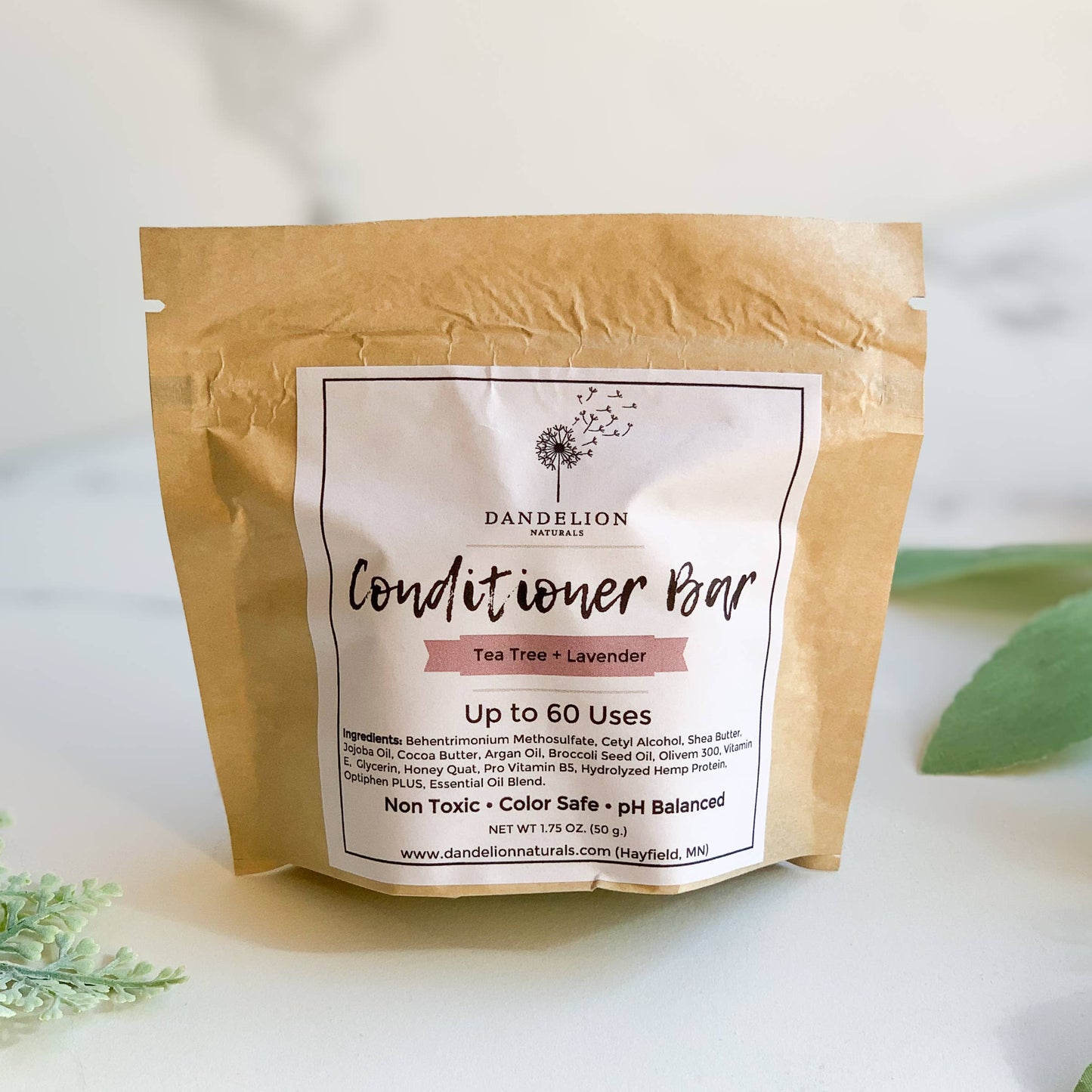 Dandelion Naturals conditioner bar tea tree lavender in brown paper packaging on white surface with green leaves